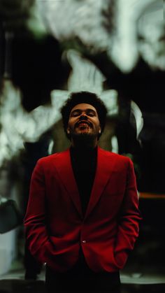 a man in a red jacket and black shirt is looking up at something behind him