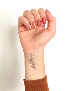 a woman's hand with a small flower tattoo on her left wrist and the other arm