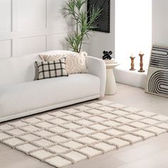 a living room with a white couch, rug and potted plant in the corner