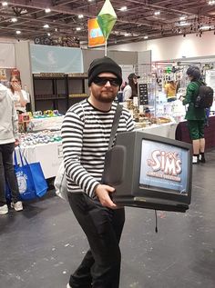 a man in striped shirt holding up an old tv