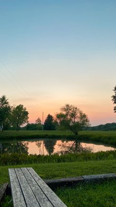 a wooden bench sitting in the grass next to a lake