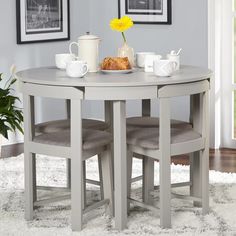 the table is set with two chairs and a breakfast tray on it, in front of some framed pictures