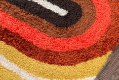 a multicolored area rug on a wooden floor with a brown, red, yellow and white design