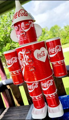 several red cups stacked on top of each other in the shape of a tower with coca - cola's written on them