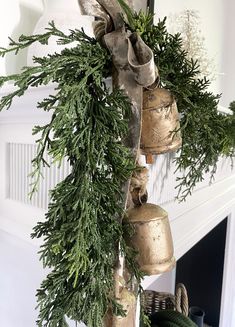 a bunch of bells hanging from the side of a fireplace with greenery on it