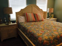 a bedroom with green walls and white shutters on the window sill is decorated with multi - colored bedding