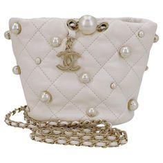 Store item: 67973 Chanel 21S White Cream About Pearls Bucket Bag Mini is a pillowy soft miniature bucket bag adorned with gold-pronged faux pearls and dangling CC charm hardware, with a woven crossbody strap. Perfect for evening or everyday, with easy access to essentials. In Cream lambskin leather and shiny gold hardware. This item is in excellent condition with very few signs of normal use. Corners are clean with no rubbing or scuffing. Hardware is clean and shiny. Interior is clean. Please view all 12 to 16 photos of the actual bag, for details, and ask any questions. Measures 6in. W (at widest point) x 4.5in. H x 4.2in. D, strap drop is 19.5 inches For 19 years, Boutique Patina has specialized in sourcing and curating the best condition vintage leather treasures by searching closets ar Chanel Pearl Bag, Chanel Bucket Bag, Navy Clutch, Navy Blue Purse, Chanel Pearl, Vintage Chanel Bag, Mini Bucket Bag, Chanel Brand, Chanel Pearls