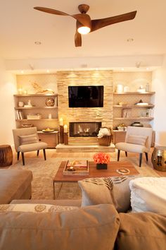 a living room filled with furniture and a flat screen tv mounted on the wall above a fire place