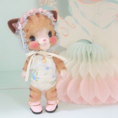 a small teddy bear wearing a diaper next to a pink and white wallpaper