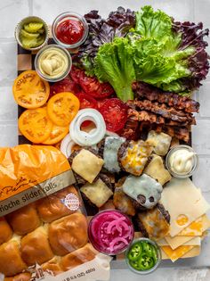 an assortment of meats, cheese and vegetables on a cutting board with sauces