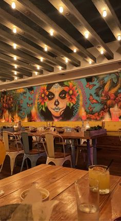 the interior of a mexican restaurant with large murals on the wall and wooden tables in front of them