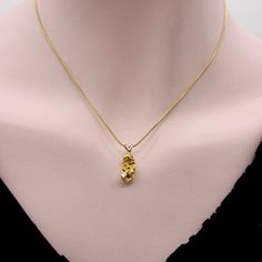 This is part of Chairish’s Fine Jewelry assortment.  This beautiful charm features a single 22k gold nugget hung from an elegant rabbit bail. A diamond is prong set into one of the recesses of the nugget, an off-center placement that works perfectly with the shape of the nugget, as if the diamond was excavated from the Earth along with the gold. The gold nugget has a wonderful texture and unique shape. The free form dimensions of gold nuggets are organic and poetic, highlighting the buttery gold and extraordinary crevices. This is a beautiful display of gold in its natural, unaltered state.   Gold nuggets are formed by hot fluids flowing through cracks deep in the Earth’s crust. Weather eventually releases the nuggets into streams and bodies of water, where they are shaped by erosion and t Fine Jewelry In Yellow Gold Nugget Shape, Fine Jewelry Yellow Gold Nugget, Yellow Gold Nugget Fine Jewelry, Gold Nugget, Metal Charm, 22k Gold, Gold Charm, Prong Setting, Fine Jewelry