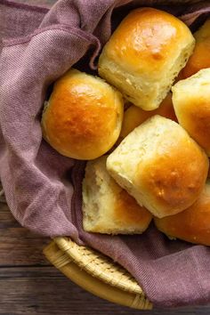 a basket filled with rolls sitting on top of a wooden table