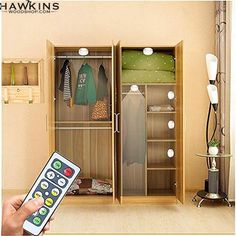 a person is holding a remote control in front of a closet with clothes and other items