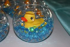 there are many small glass bowls with little rubber ducks in them and blue beads on the bottom