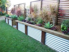 an outdoor garden with various plants and flowers in the planter boxes on the fence