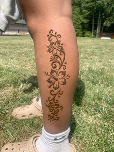 a woman's leg with a tattoo on it in the middle of a field