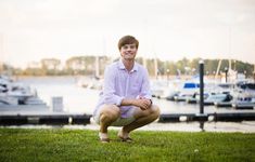 a man sitting on the grass in front of some boats