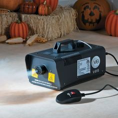 a black and yellow air dryer sitting on top of a floor next to pumpkins