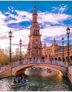 people are riding on boats in the water near a bridge with a clock tower behind them