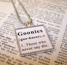 two necklaces sitting on top of an open book with the words goonies written in it