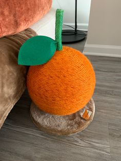 an orange ball sitting on top of a pile of pillows next to a pillow with a green leaf