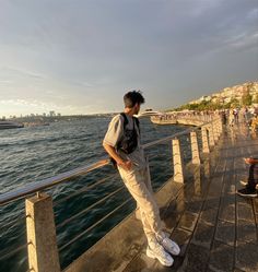 a man standing on the edge of a pier looking at the water and buildings in the background