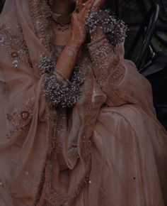 a woman in a wedding dress holding her hands up to her face while sitting down