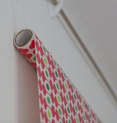 a red and green patterned tie hanging from a hook on the wall next to a white door