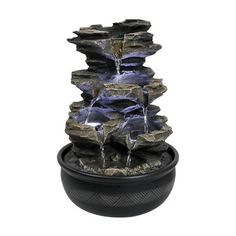 an outdoor fountain with water running from it's sides and rocks on the bottom