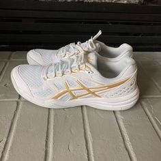 a pair of white and gold running shoes