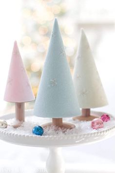 three small christmas trees sitting on top of a white cake plate