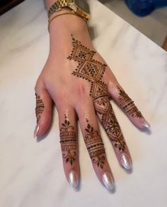 a woman's hand with henna tattoos on it