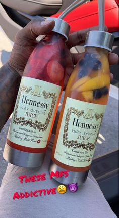 someone holding two bottles of fruit juice in their hands with the words hennessy on it