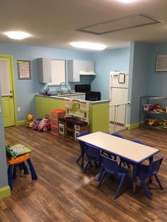 a child's playroom with blue walls and wooden flooring, including two children's table and chairs