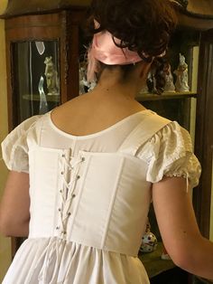 A corset from the early 19th century, 1st Empire or Regency. It is a short corset that is laced in front and behind, which allows an impeccable adjustment with the lacing.  Size M corresponding to 82cm under the chest, this corset is suitable for a B or C chest. Carefully made in soft white cotton, it requires a delicate wash at 30 C degrees. Worn over the day shirt, it will be your Jane Austen, Bridgerton or Napoleon costume accessory. White Fitted Corset With Lace-up Back, Regency Style Overbust Corset Dress, Regency Corset Dress With Fitted Bodice, Regency Style Fitted Bodice With Corset Back, Regency Style Overbust Fitted Corset, Regency Style Overbust Corset, Regency Style Fitted Overbust Corset, Regency Style Overbust Corset With Fitted Bodice, Regency Style Fitted Corset Dress With Boned Bodice