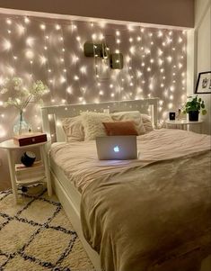 a laptop computer sitting on top of a bed in front of a wall with lights