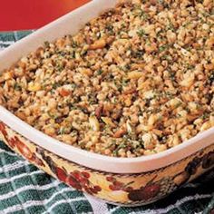 a casserole dish filled with rice and nuts on a green cloth next to a red plate