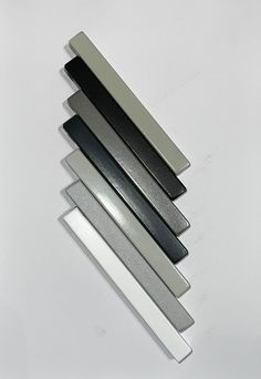 four different colors of glass on a white surface with one black and one silver color