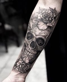 a person with a skull and roses tattoo on their arm, holding onto a hand