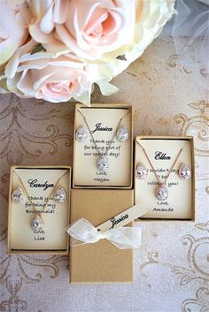 three personalized necklaces in boxes next to a bouquet of pink roses on a table