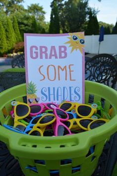 a green basket filled with sunglasses and a sign that says grab some shades on it