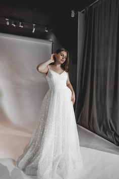 a woman standing in front of a white backdrop wearing a dress with stars on it