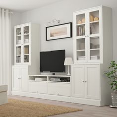 a living room with white furniture and a flat screen tv on top of a entertainment center