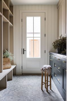 a large walk in closet next to a white door with two stools on it