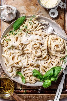 a bowl filled with pasta and sauce on top of a wooden cutting board next to silverware