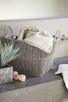 a basket sitting on top of a counter next to a potted plant and towel