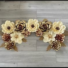 paper flowers are arranged on the floor in a row with gold leaves and brown centers