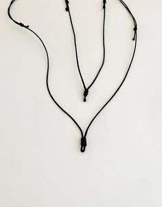 a black cord with two small beads hanging from it's end on a white surface