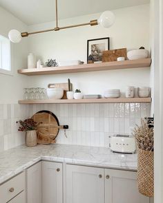 a white kitchen with wooden shelves and marble counter tops